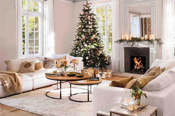 Salón acogedor con árbol de Navidad, chimenea encendida y una alfombra blanca que aporta calidez y suavidad al ambiente.
