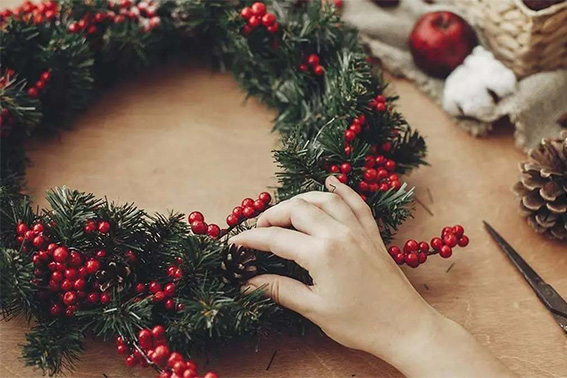 Creación de una corona navideña artesanal con elementos naturales como ramas y bayas.