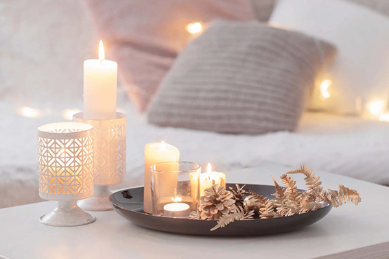 Conjunto de velas en diferentes tamaños y candelabros sobre una mesa, creando un ambiente cálido y acogedor